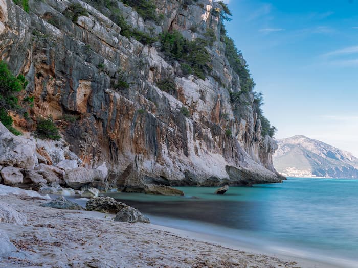 My Summer 10-Day Secret Italy Itinerary: Hidden Beaches & Island Bliss Stunning aerial view of Cala Gonone beach with white pebbles and turquoise crystal water, Orosei Gulf, Sardinia